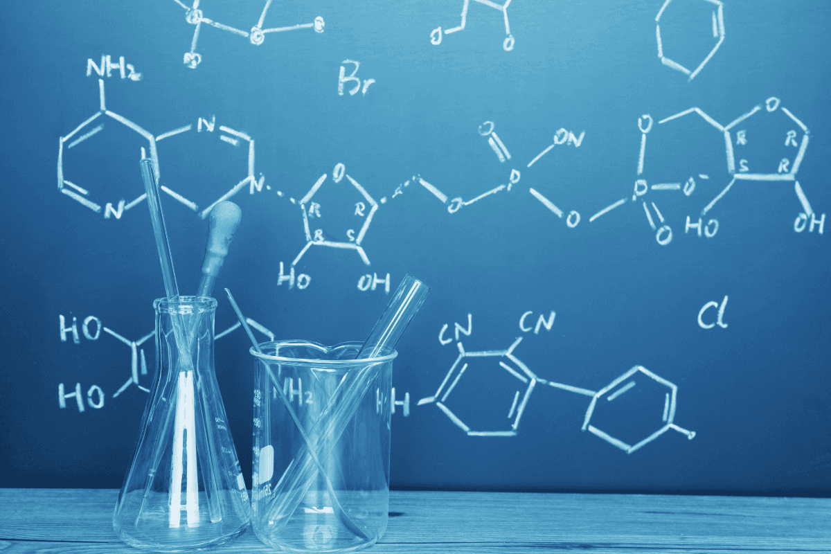 Laboratory glassware against a chalkboard of molecular structures